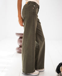 Person wearing wide leg jeans in army green, indoors.
