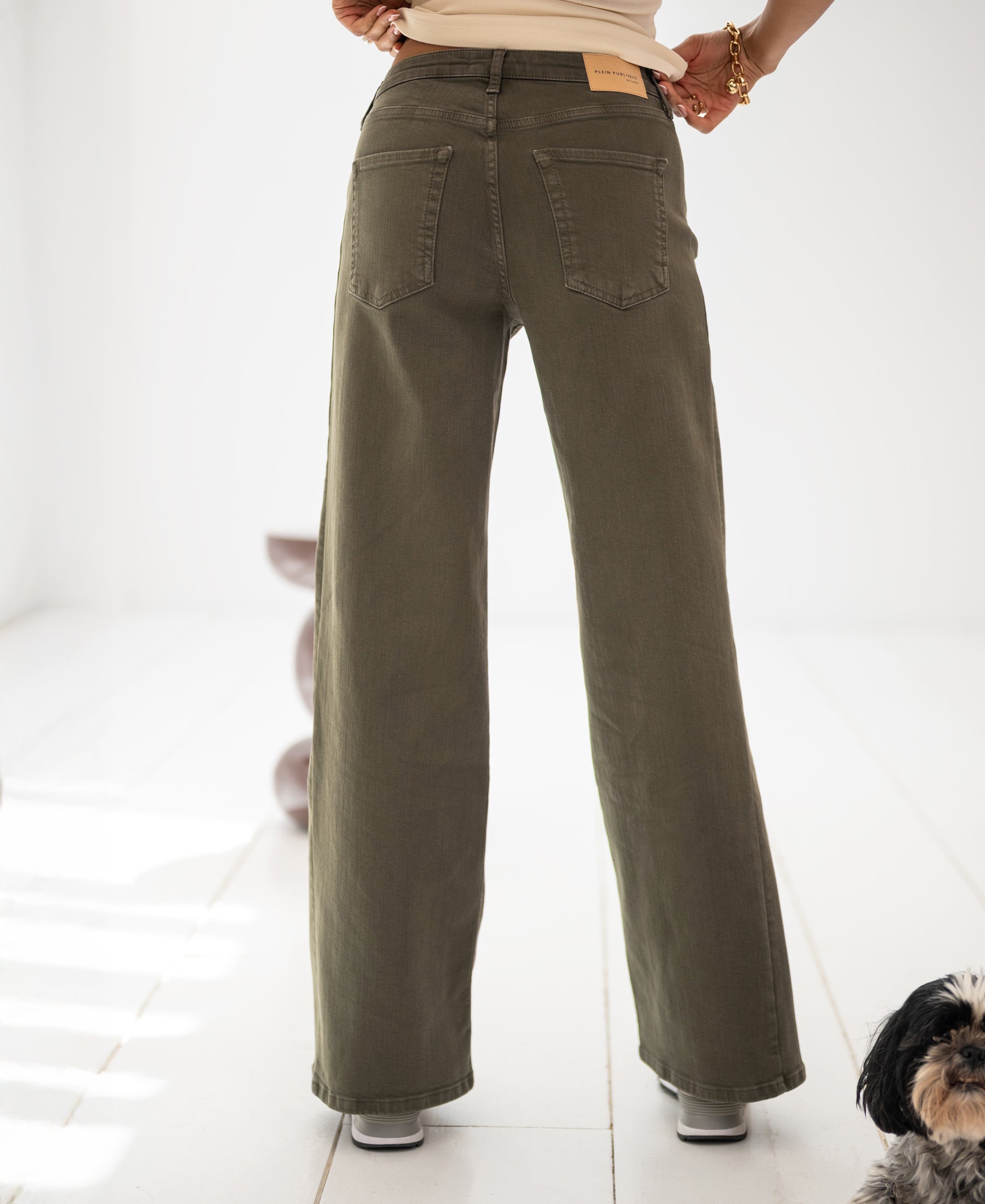 Wide leg army green jeans in a bright room.