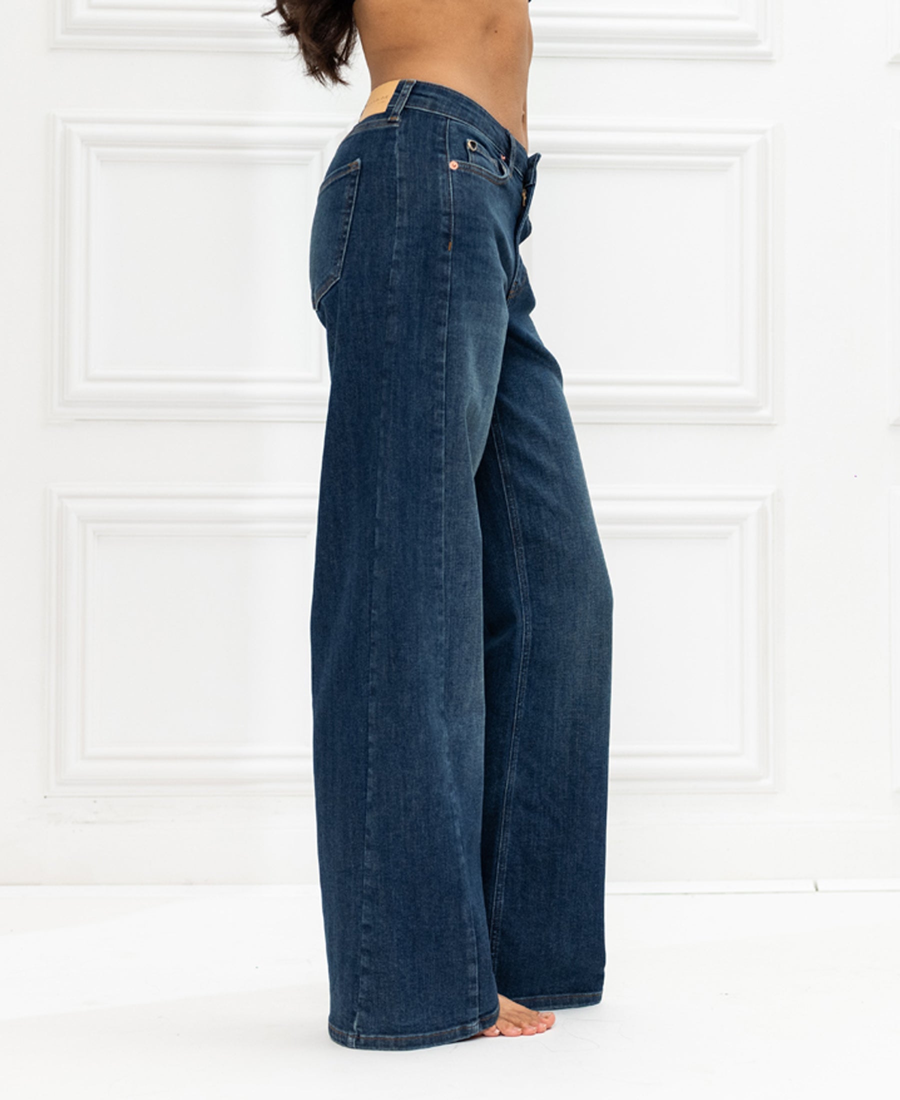 Wide leg blue heritage jeans shown against a white paneled background.
