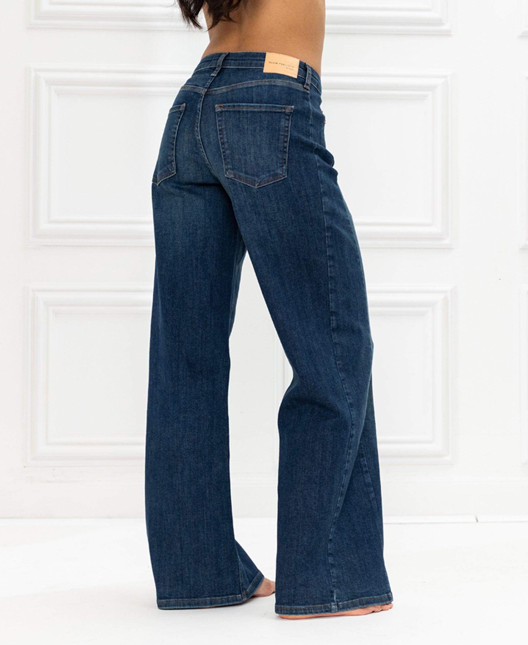 Wide leg blue heritage jeans, displayed in a white paneled room.