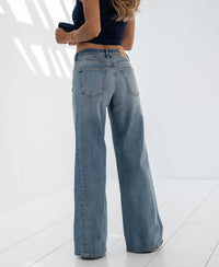 Person wears light stone wide leg jeans in a bright, minimalist room.