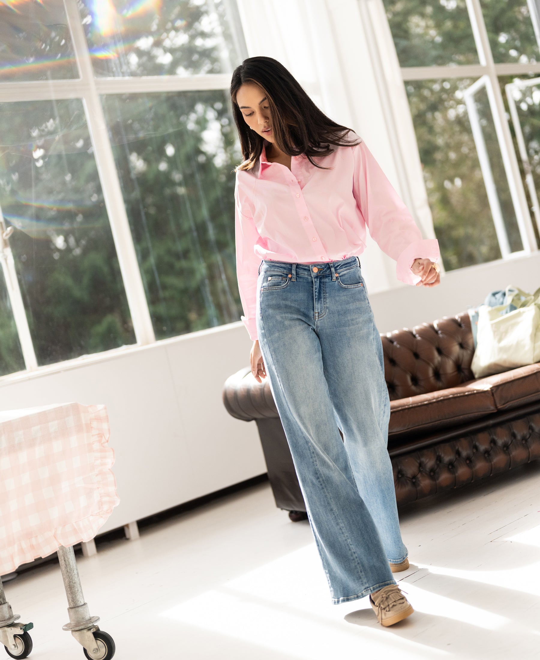 Wide leg jeans in light stone color, shown indoors near a window with sunlight.