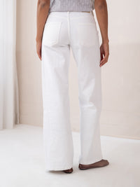 Back view of person indoors wearing wide leg white jeans.