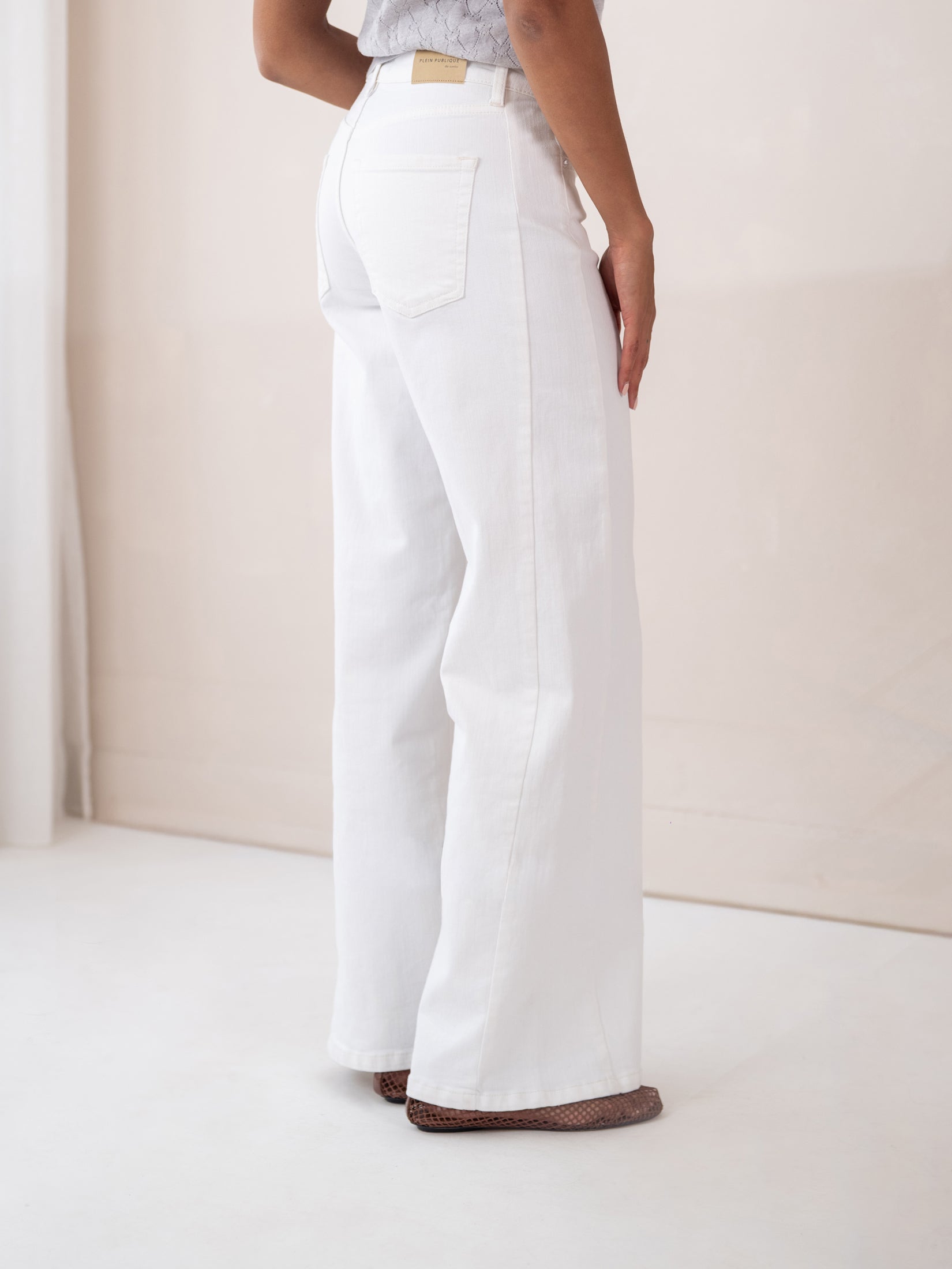 Wide leg jeans LE SPICE White by PLEIN PUBLIQUE, shown from the back in a bright room.