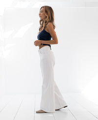 Wide leg white jeans shown in profile in a bright white room.