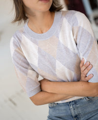 Light grey melange argyle merino wool sweater with short sleeves, shown worn by a woman, arms crossed.