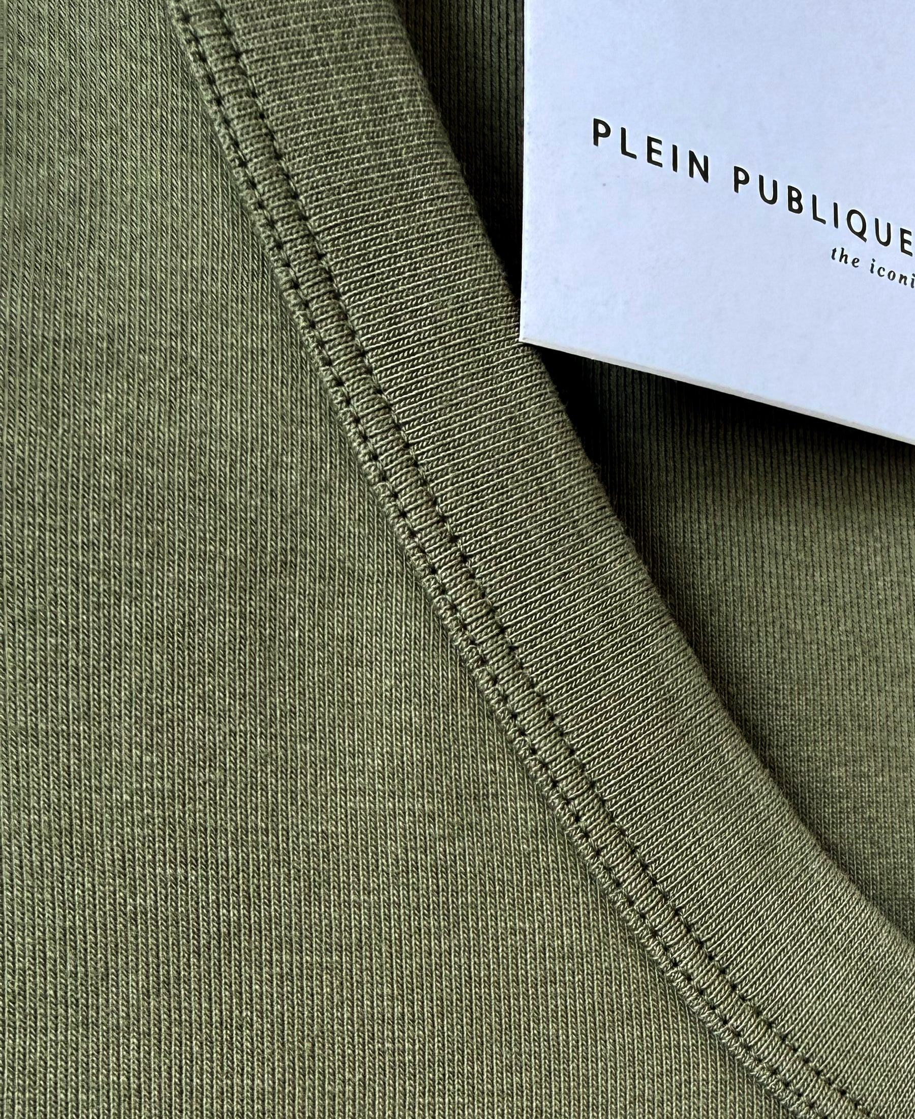 Close-up of the luxe and soft olive green top’s rib collar with a PLEIN PUBLIQUE tag visible.