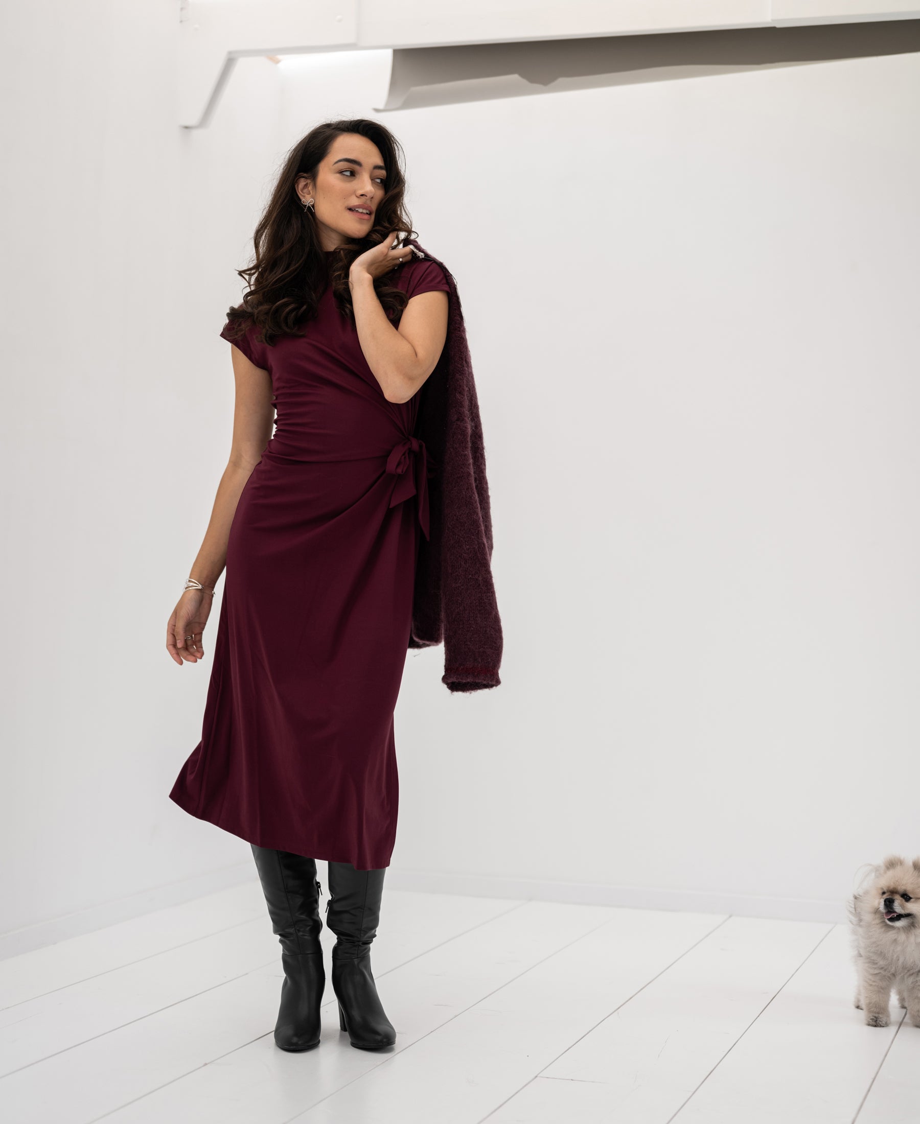Woman wears a PLEIN PUBLIQUE LA TOULOUSE Bordeaux travel dress, posing indoors.