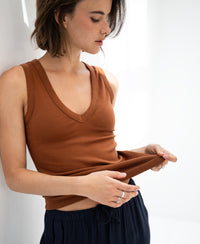 PLEIN PUBLIQUEs luxe and soft brown LA VALE top, shown on a woman standing by a white wall, looking down.