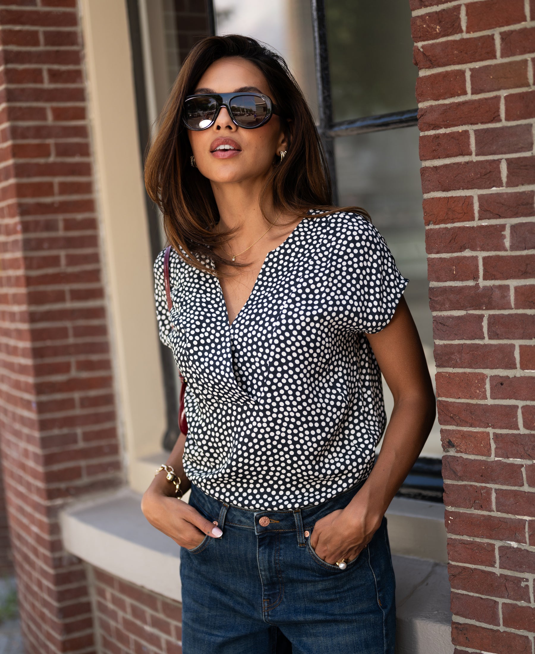 Charcoal dot print Stippen top by PLEIN PUBLIQUE shown from the front against a brick wall.