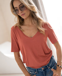 Bright terra bamboo T-shirt LES VERSAILLES by PLEIN PUBLIQUE worn indoors, shown on a woman with long blonde hair.