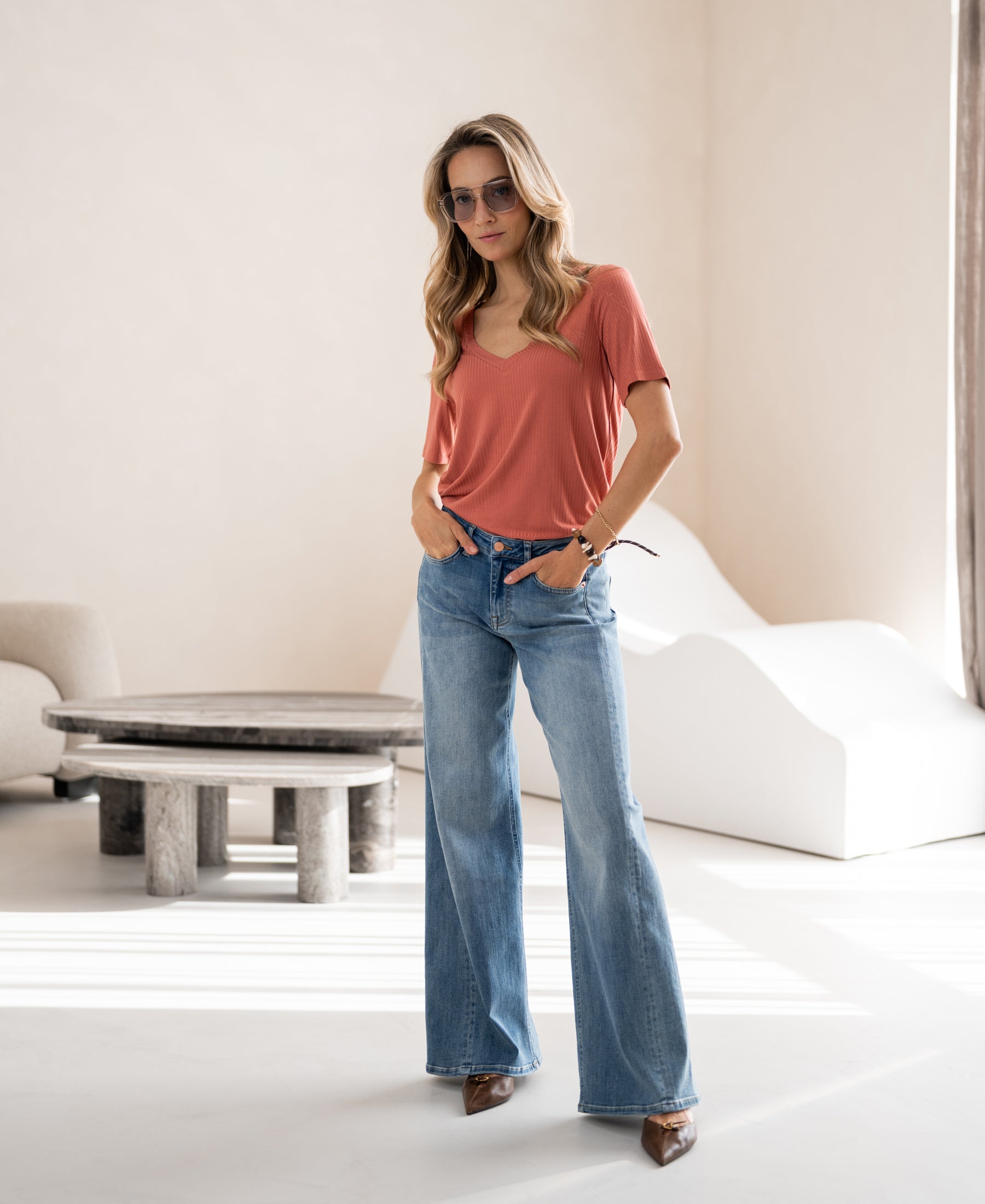 Woman wearing bamboo T-shirt Les Versailles by Plein Publique in a modern neutral room.