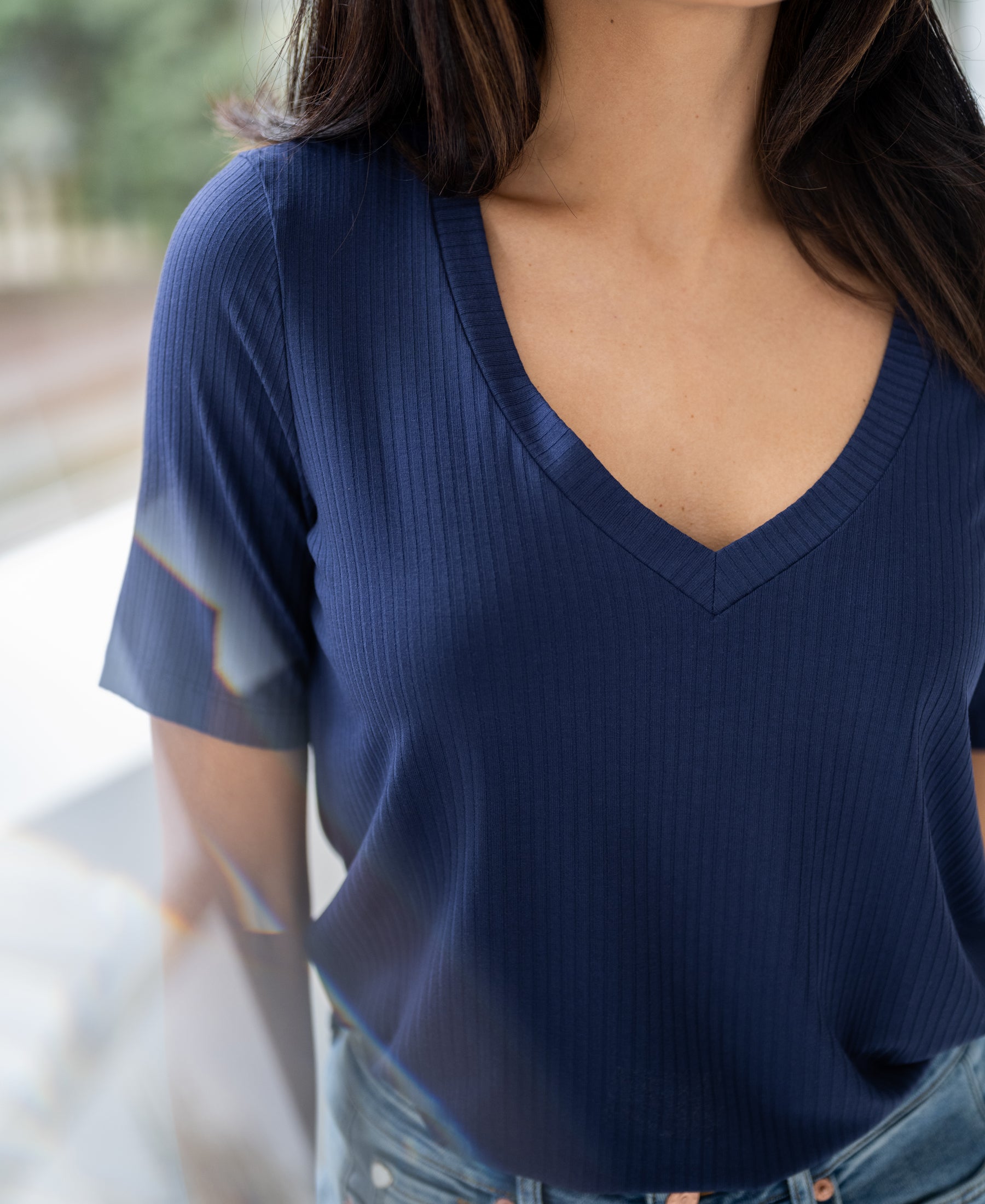 Woman wearing a PLEIN PUBLIQUE bamboo T-shirt LES VERSAILLES Indigo, indoors with blurred background.