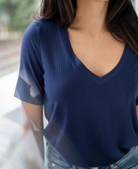 Woman wearing a PLEIN PUBLIQUE bamboo T-shirt LES VERSAILLES Indigo, indoors with blurred background.