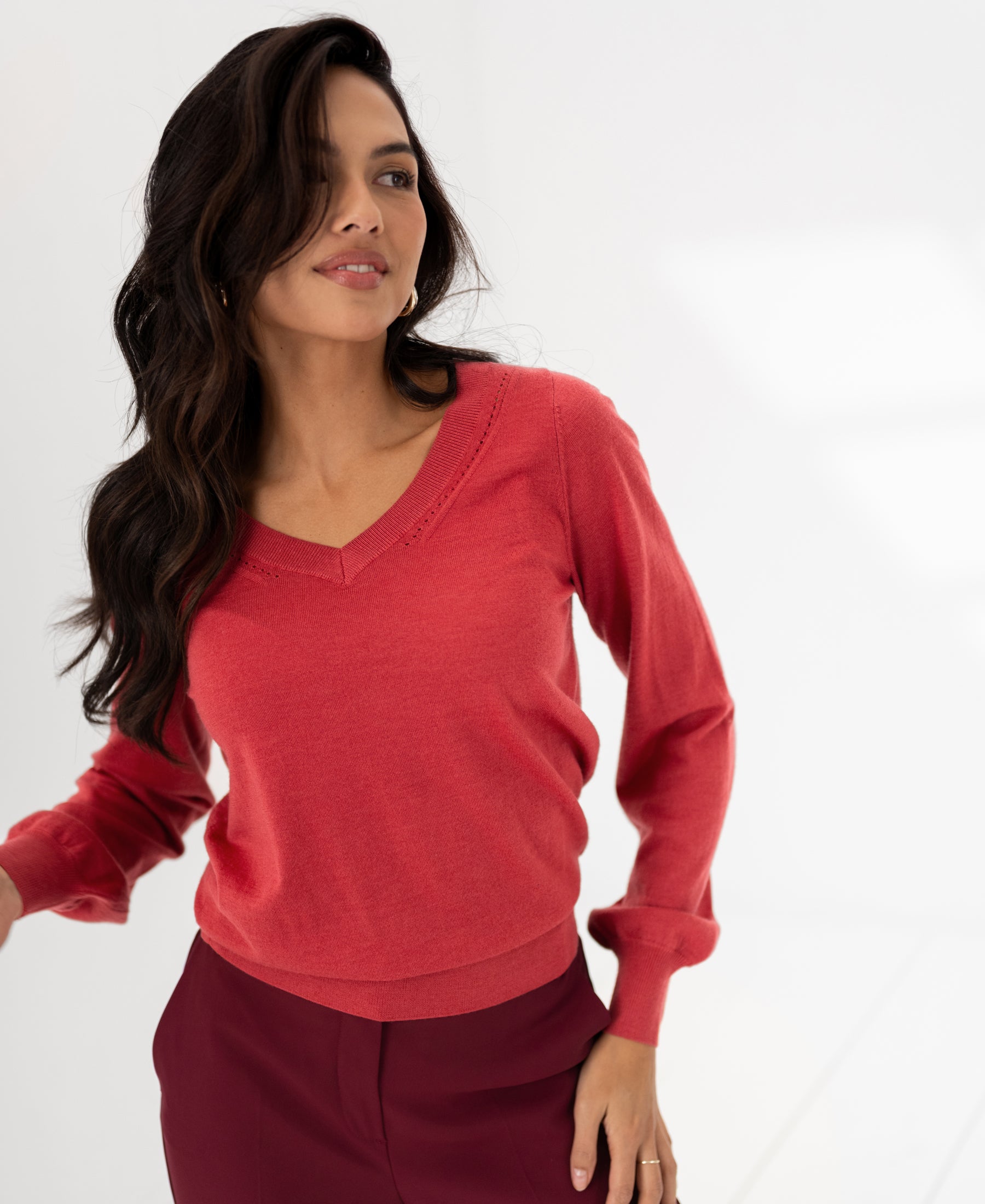 PLEIN PUBLIQUE Merino wool V-neck sweater LA VILLE in red, shown on a model in a minimal room.