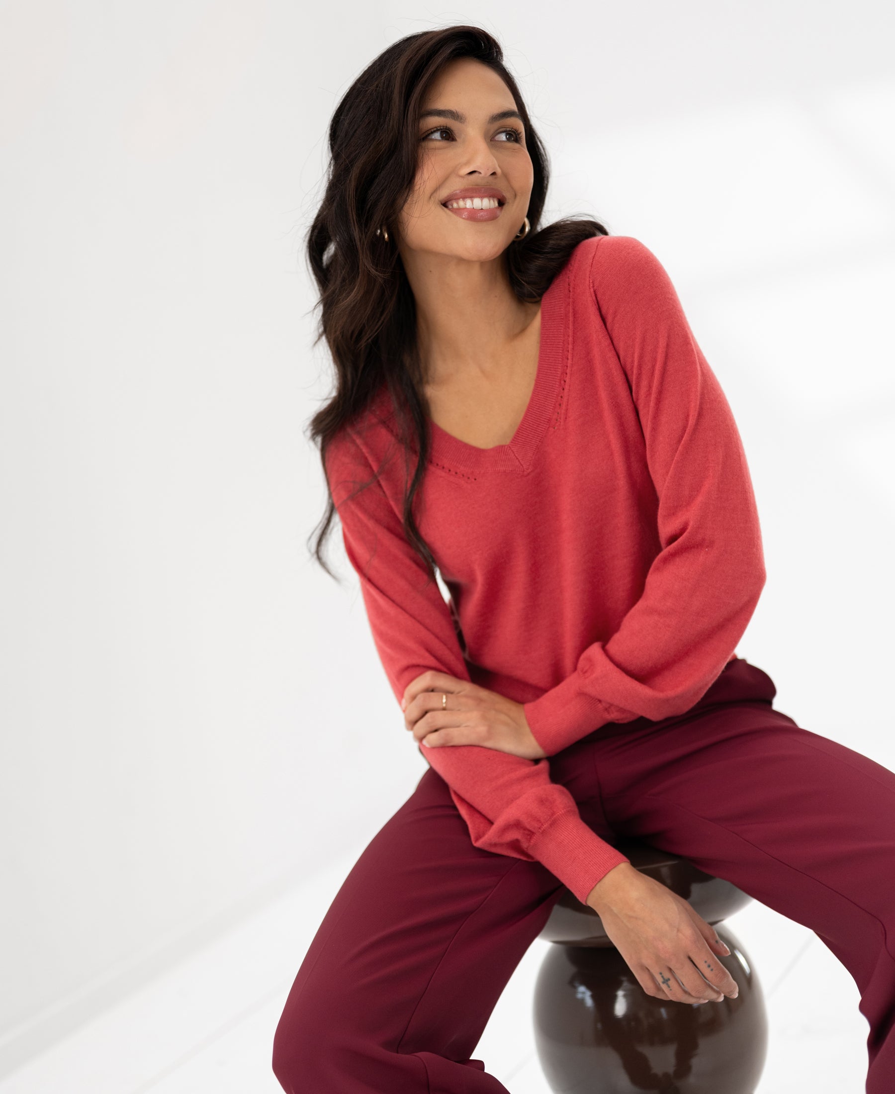 Red merino wool V-neck sweater by PLEIN PUBLIQUE shown in a bright, minimal space.