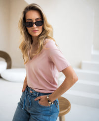 Woman wearing a PLEIN PUBLIQUE pink stretch short-sleeve T-shirt indoors.