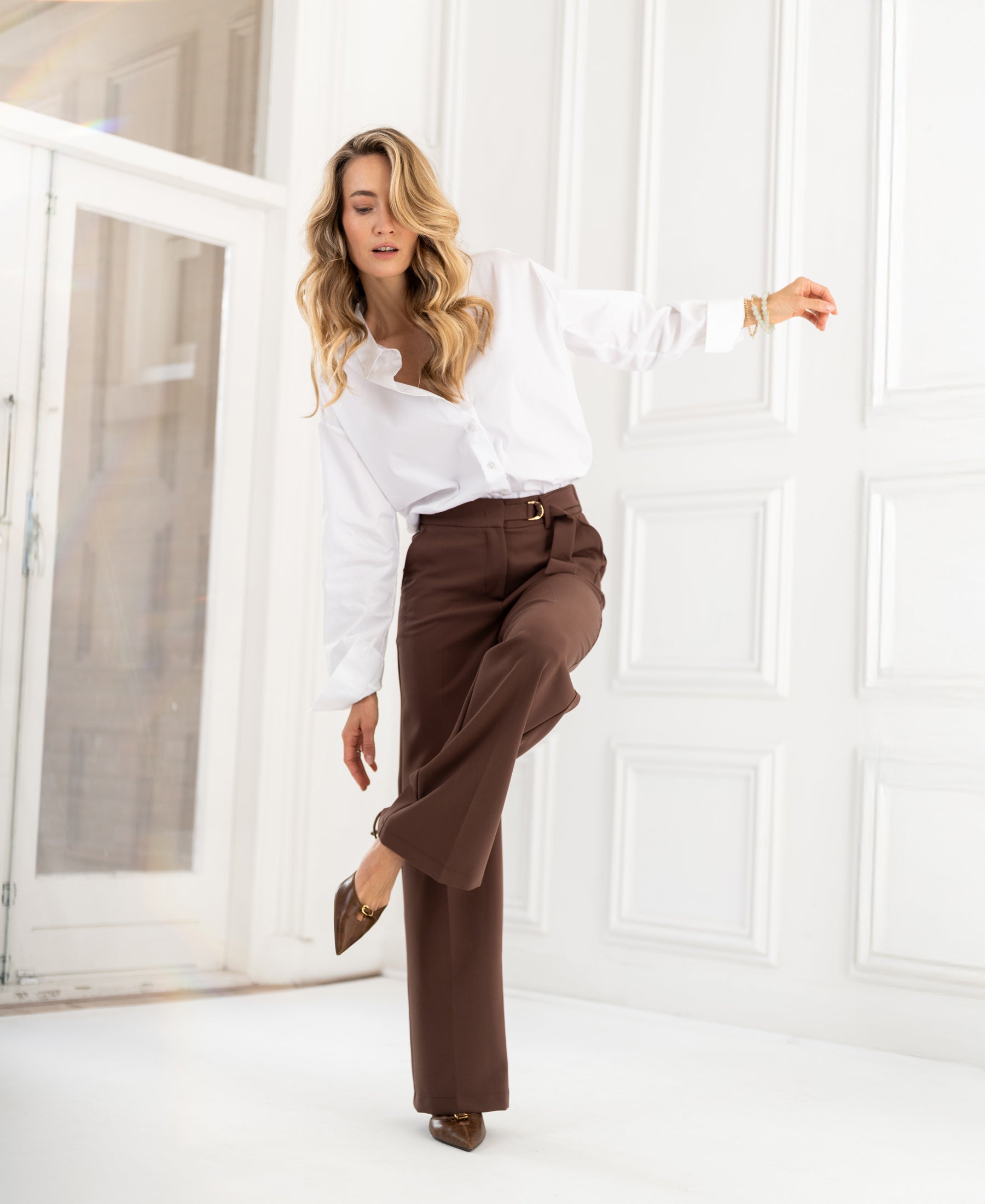 Brown pants in a bright white room with panel walls.