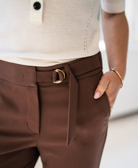 Model wears brown LA WENDE trousers, hand casually in pocket.