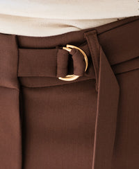 Close-up of women's stretch cacao brown trousers with belt and gold buckle.