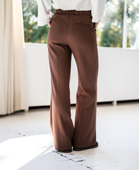 Brown LA WENDE pants by PLEIN PUBLIQUE, shown indoors near sunlit windows.