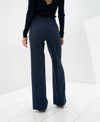 Dark blue PLEIN PUBLIQUE LA WENDE pants, shown from the back on a white floor.