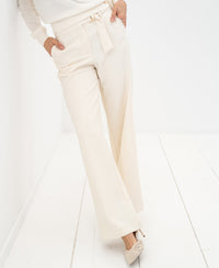Cream wide-leg stretch trousers by PLEIN PUBLIQUE, shown in a white room.