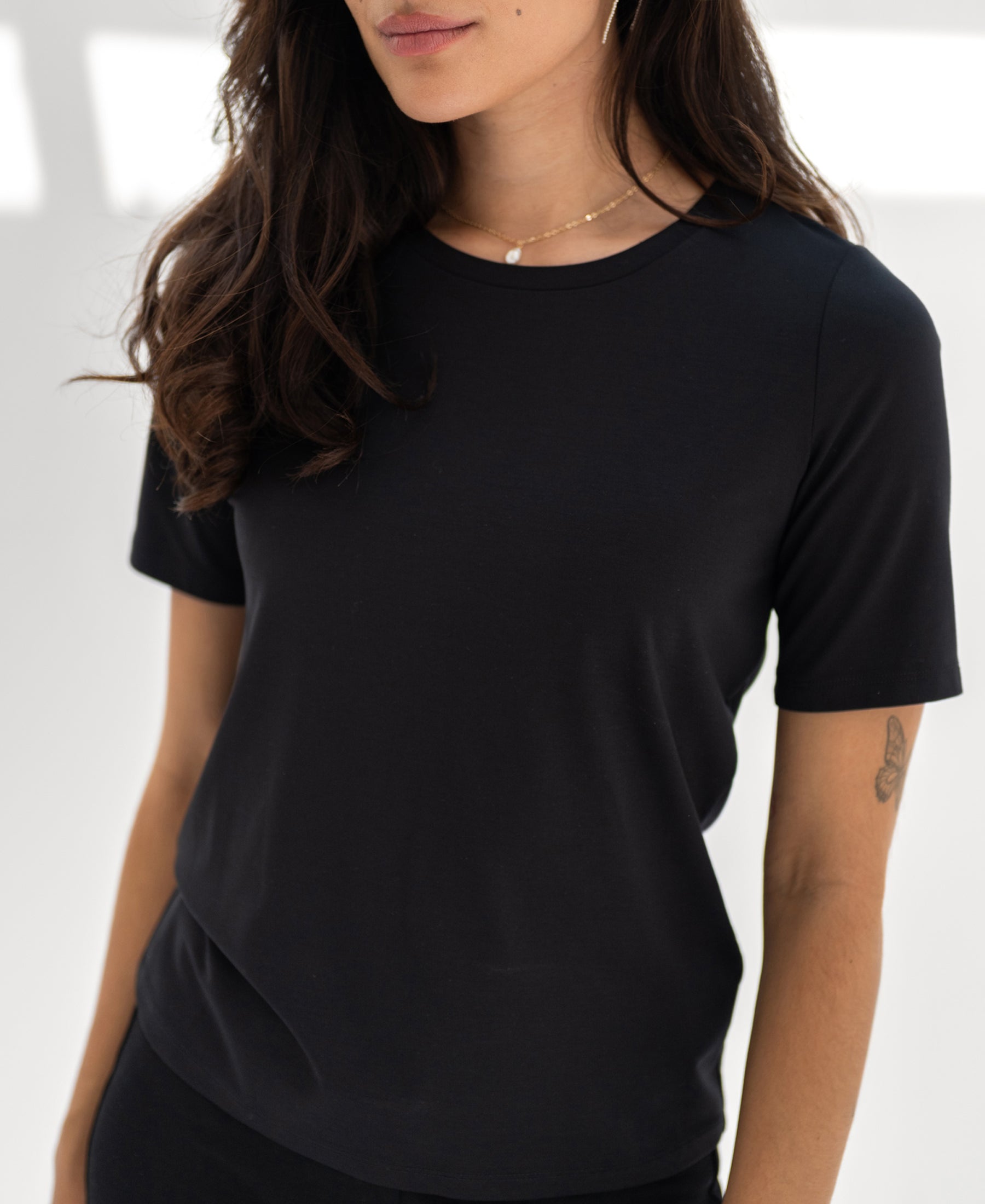 Woman wearing a black travel T-shirt by PLEIN PUBLIQUE, LE FAVORY style.